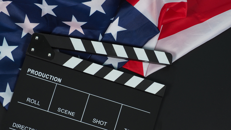 Black movie slate and flag of the United States of America on black background.