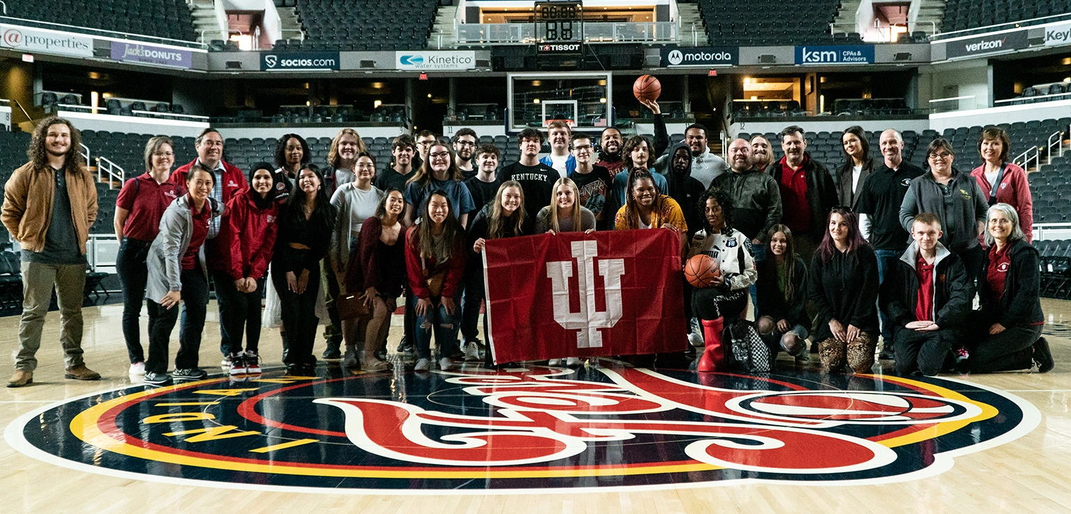 Students and faculty pose for a picture on the Indiana Fever basketball court.
