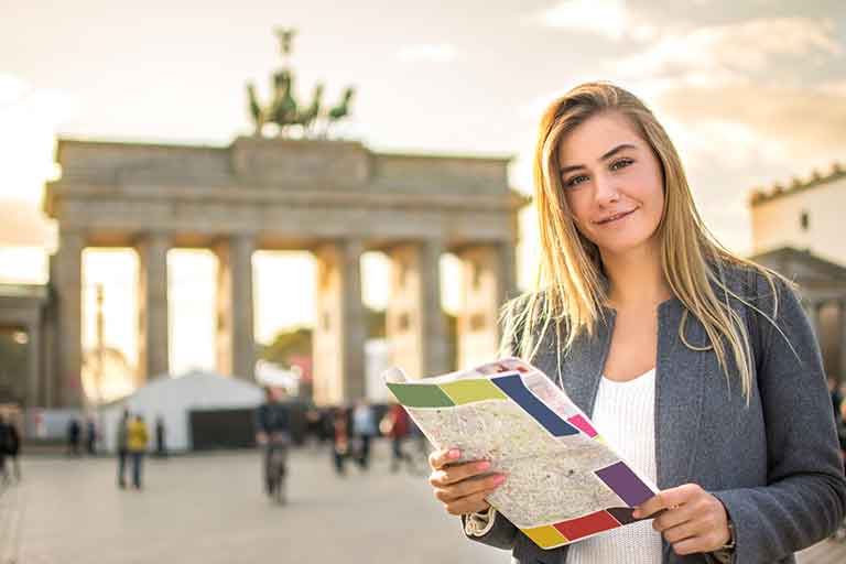 Female student in Germany holding a map and smiling