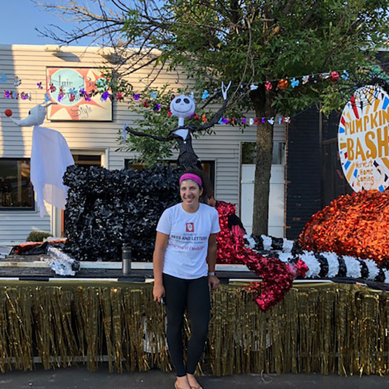 Woman standing in IU Southeast shirt in front of float for Harvest Homecoming parade