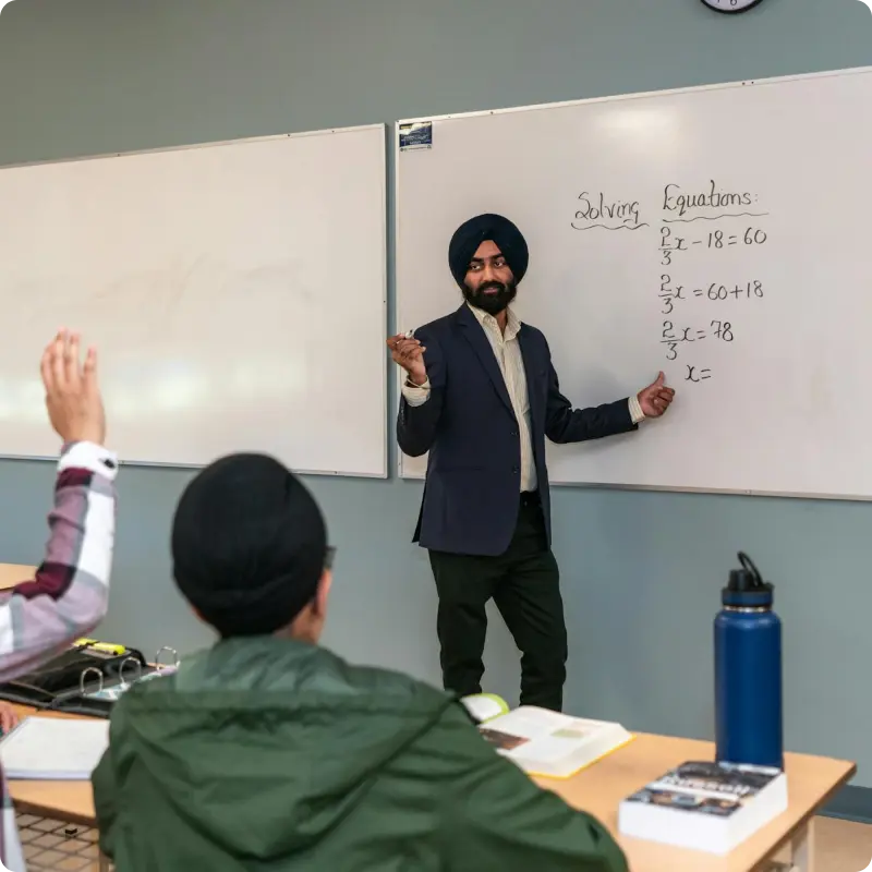 Male professor at a whiteboard teaching math to a classroom