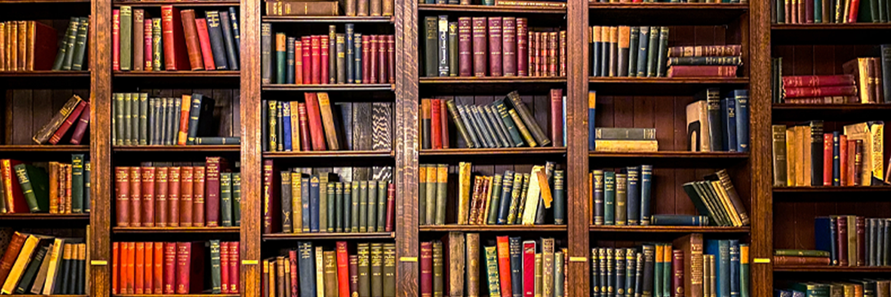 Books and other educational materials on a desk in front of a chalkboard containing mathematical equations.