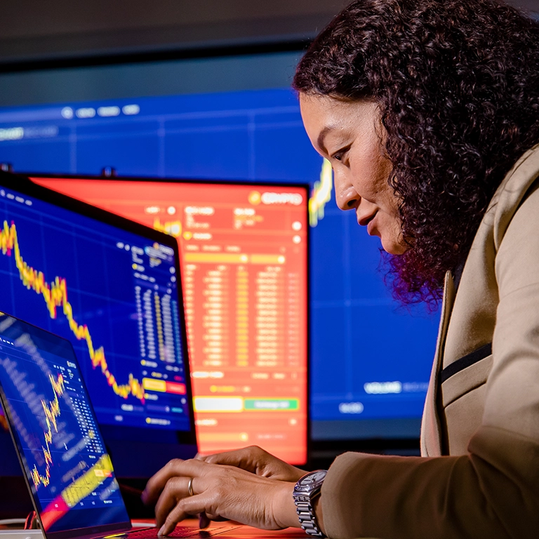 Dark-skinned woman in a blazer working at a computer.