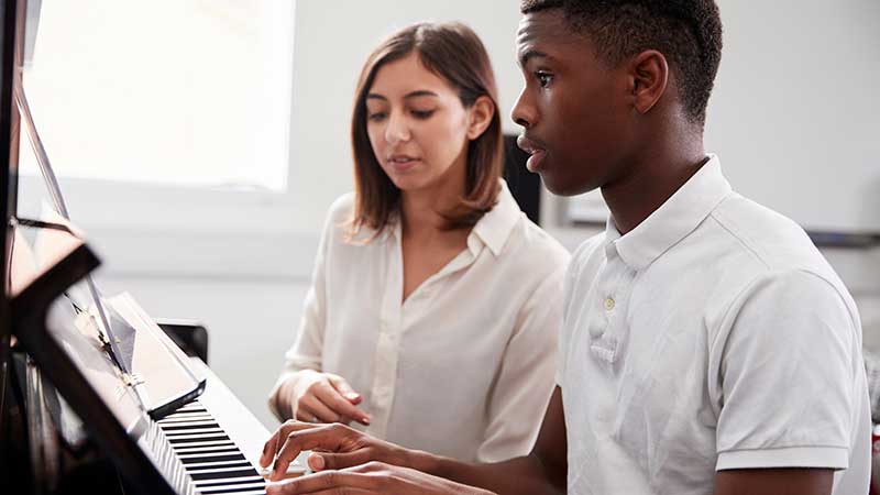 Instructor helping a student learn to play the piano