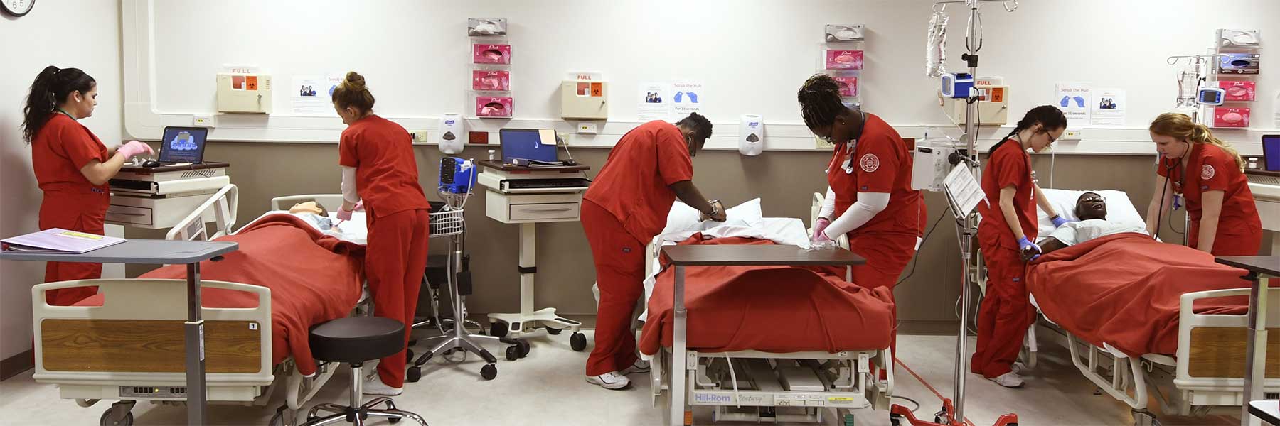 Three pairs of two IU Southeast nursing students performing simulations at different patient beds