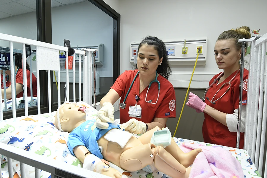 Four IU Southeast nursing students treating simulated adult patients in a lab