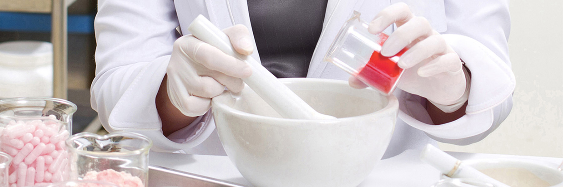 Lab technician in a pharmacy setting using a mortar and pestle.