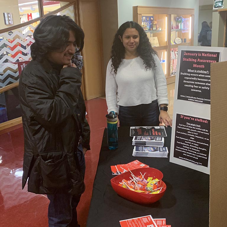 A male and female student at a tabling event about stalking awareness.